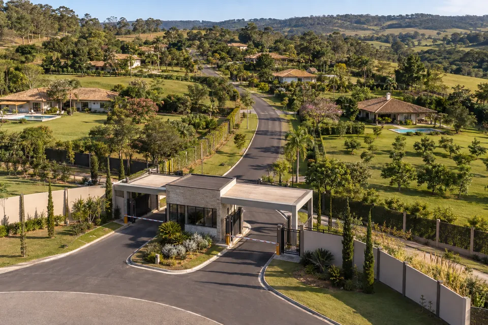 Vista aérea de condomínio residencial com portaria, ruas pavimentadas e áreas arborizadas