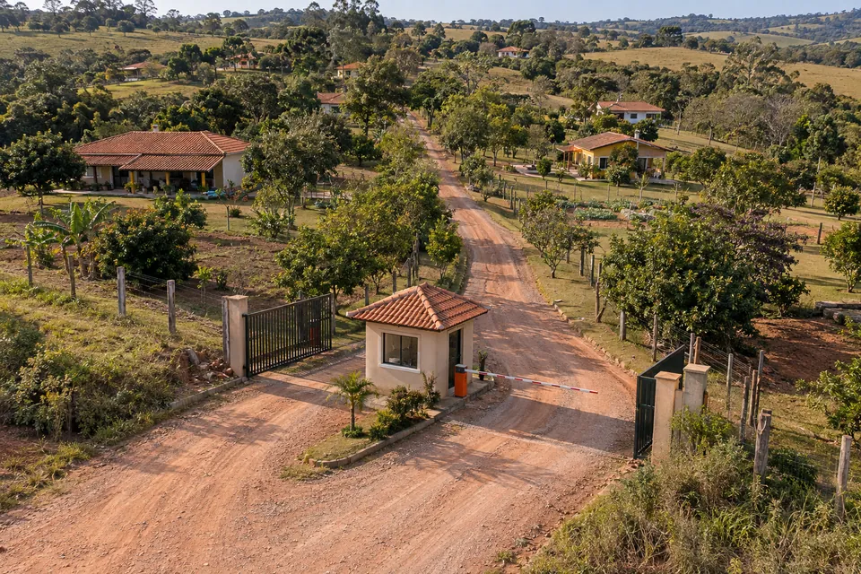 Entrada de conjunto residencial com guarita, casas e áreas verdes